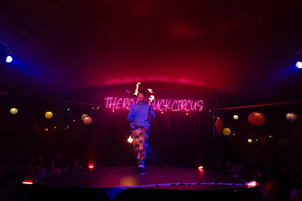 A fire juggler on the round stage at Fête du Puck in Walthamstow, the audience circling the ring