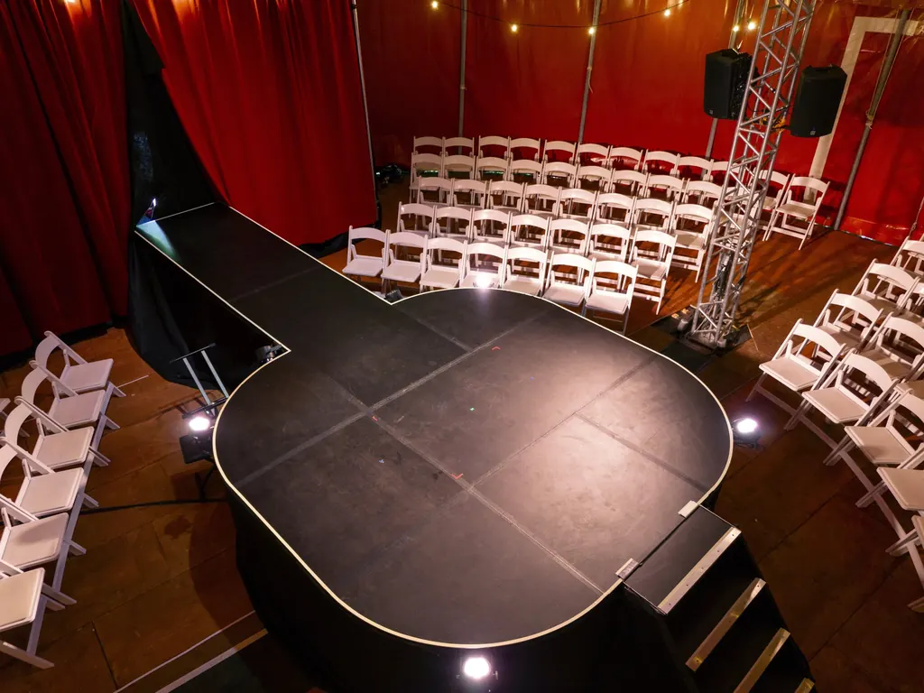 Inside Little Puck: a thrust stage, white chairs and wooden floor