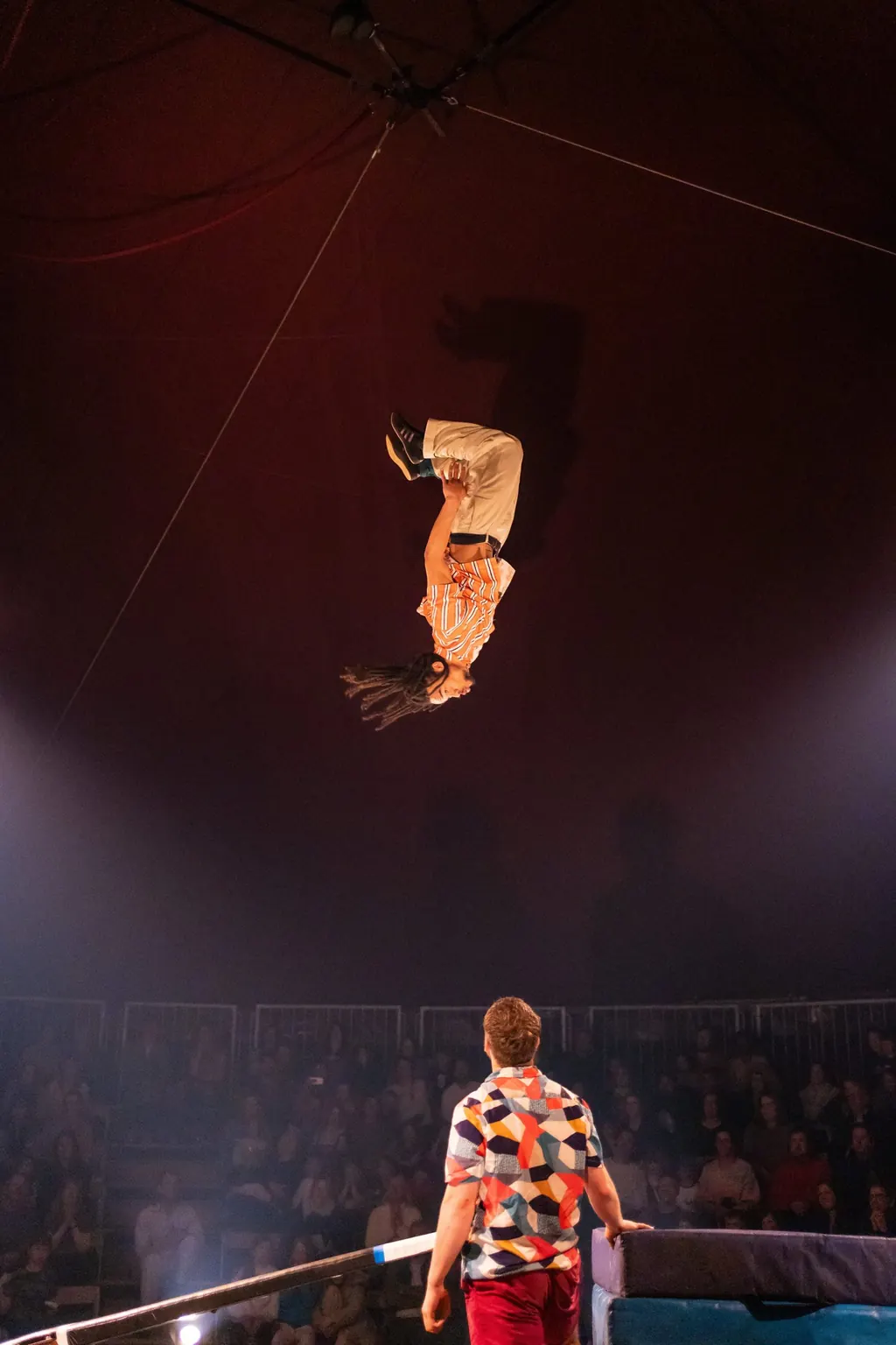 A Revel Puck aerialist mid-show, high above the ring