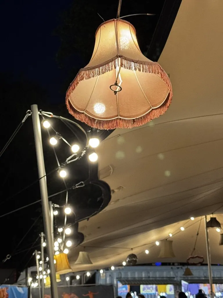 A fringed lampshade and festoon lights inside our stretch tent