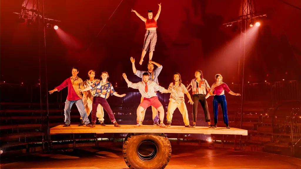 The Wing-Scuffle troupe balanced on the Giant Rola Bola in the Revel Puck big top